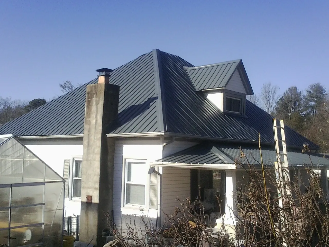 Dark blue standing seam metal roof on a white farmhouse with dormer — Slate & Tile Roof Repair by Roofing Brothers in Haverstraw