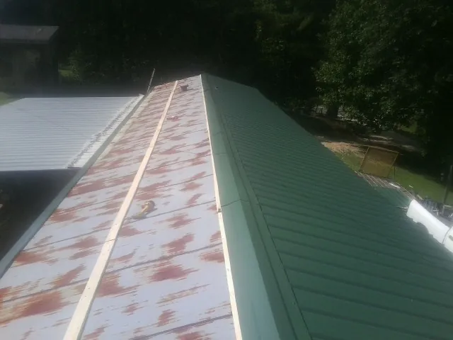 Old rusted panels beside newly installed green metal roofing — Wind Damage Roof Repair by Roofing Brothers in Haverstraw