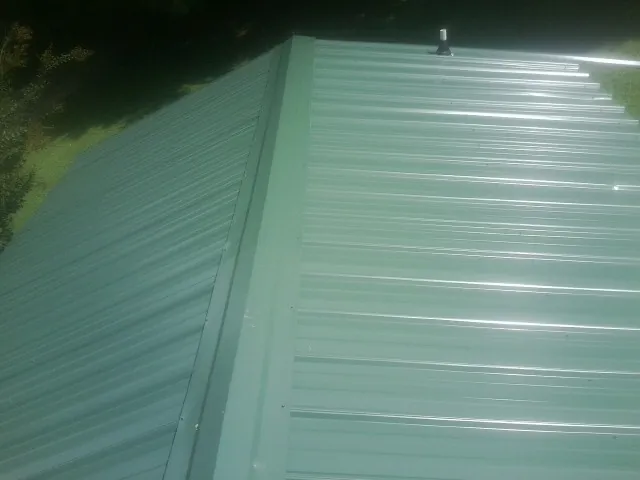 New green metal panels meeting at the ridge of a roof — Flat Roof Repair work by our crew in Haverstraw