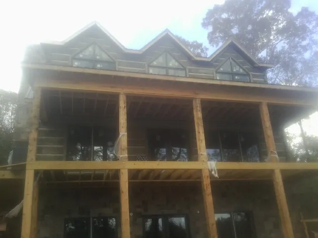 Dormers and porch framing on a large log home under construction — Roof Coating work by our crew in Haverstraw