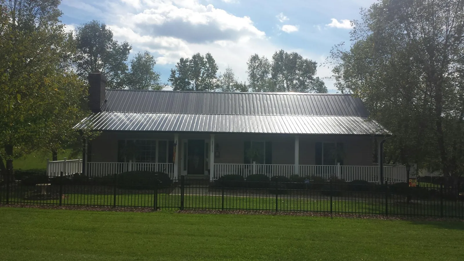 Gray metal roof on a brick ranch with a full width front porch — Gutter Guard Installation work by our crew in Haverstraw