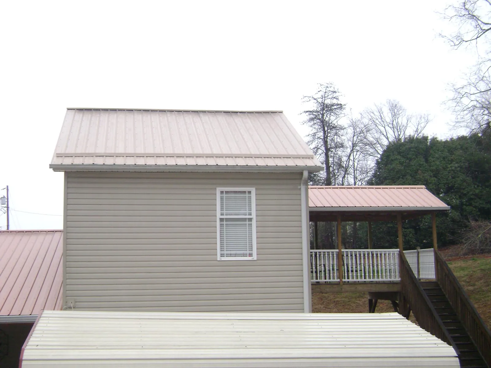 Tan metal roofs on a two story addition and attached porch, from a Roof Replacement job in Haverstraw