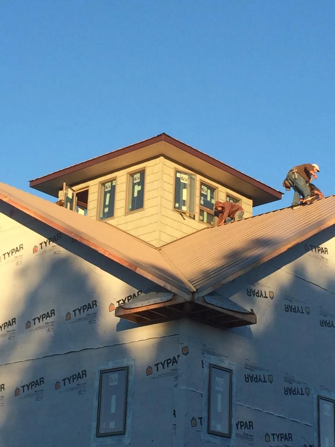 Roofers working around a rooftop cupola on a new metal roof at sunset — Roof Waterproofing in Haverstraw by Roofing Brothers